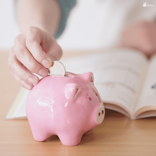 Hand placing money into a piggy bank as part of a savings strategy and long-term budgeting plan.