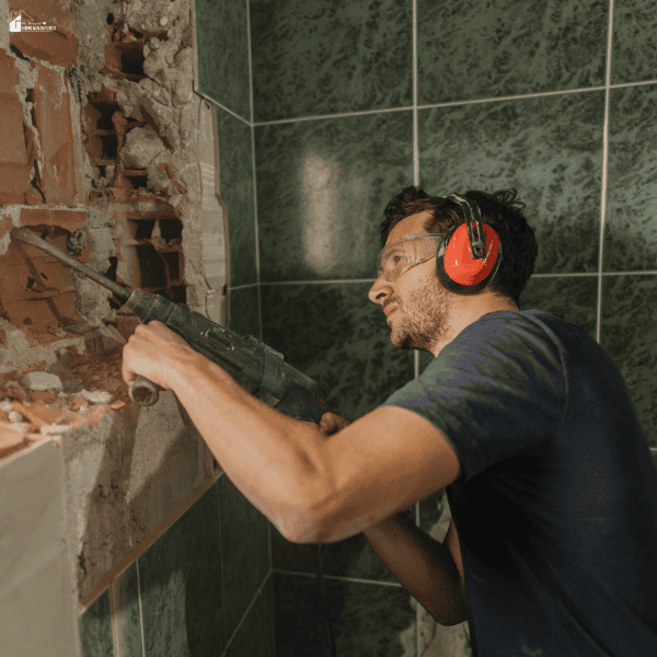 Contractor removing old wall materials during a bathroom remodel to prepare the space for updated fixtures, plumbing, and finishes.