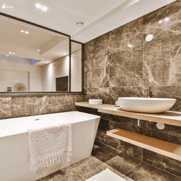 Modern bathroom with elegant stone tile, a freestanding soaking tub, and a vessel sink that creates a luxurious spa-like atmosphere.