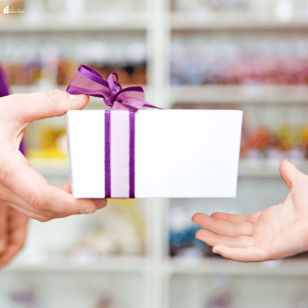 An adult hands a wrapped gift to a child, representing a practical gift that children can enjoy and use every day.