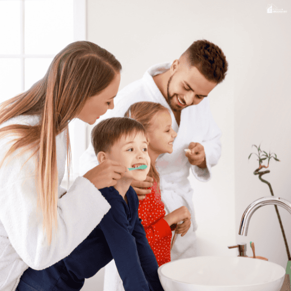 A family brushes their teeth together in a bright bathroom, showing healthy daily hygiene habits for parents and children.
