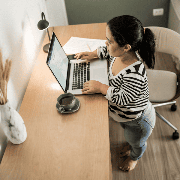 A shorter person works comfortably at an adjustable standing desk with an ergonomic setup that supports proper posture.