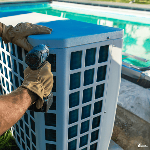 Technician installing an electric pool heat pump beside a backyard swimming pool to improve water temperature and extend the swimming season.