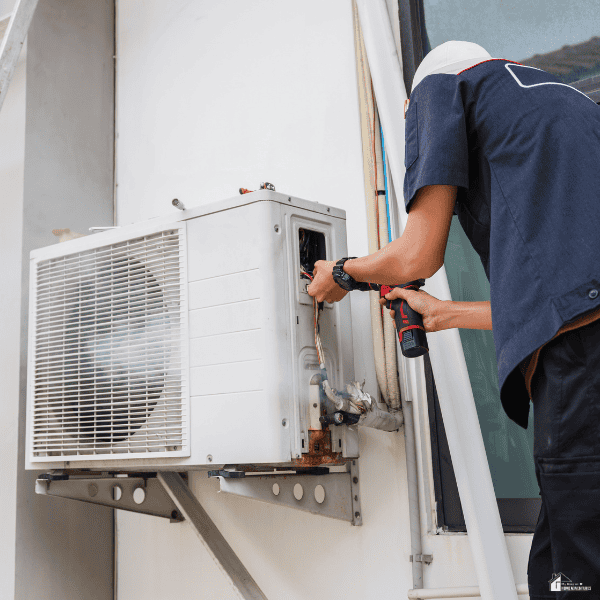 HVAC technician inspecting an outdoor air conditioning unit to diagnose early signs of mechanical issues.