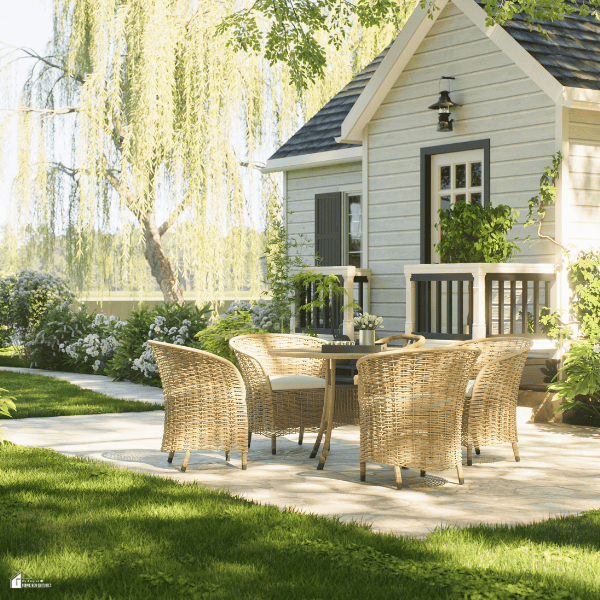 Cozy backyard patio with woven outdoor furniture, lush landscaping, and a charming garden setting that creates an upscale outdoor living space on a budget.
