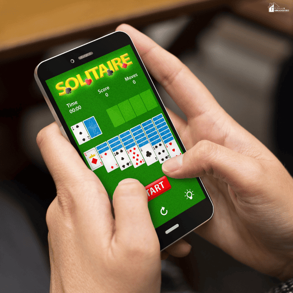 Hands holding a smartphone while playing a digital card game, highlighting free online solitaire games on a mobile device.
