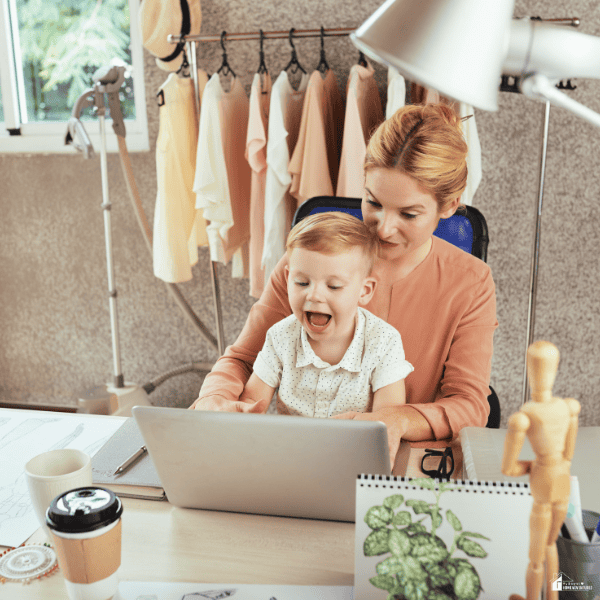 Stay-at-home mom working on a laptop with a young child nearby, illustrating the balance of parenting and running a home-based business.