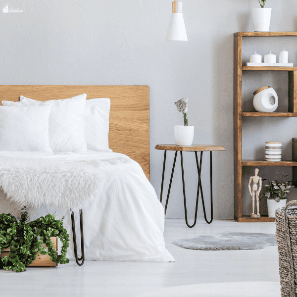 Minimalist bedroom with white bedding, natural wood furniture, indoor plants, and soft textures creating a cozy and luxurious retreat atmosphere.
