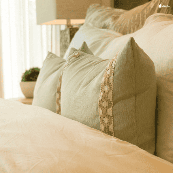 Neutral-toned decorative pillows layered on a bed, showcasing natural fabrics and cozy bedroom styling with a warm, elegant aesthetic.