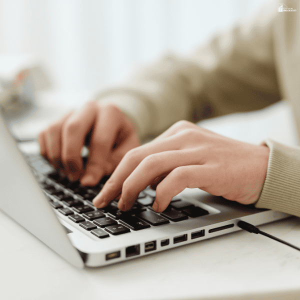 Close-up of a student typing on a laptop while using digital tools for GCSE exam preparation.