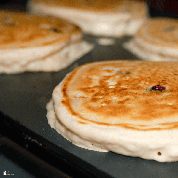 Golden pancakes cooking on a flat-top griddle, showing an easy breakfast option for outdoor griddle cooking.