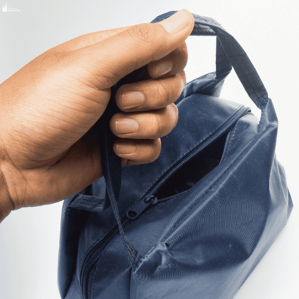 Hand holding a compact navy insulated lunch bag with a zippered top and carrying handles.