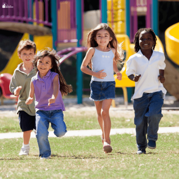Four young children run together on a school playground, showing active participation, friendship, and confidence during outdoor activities.
