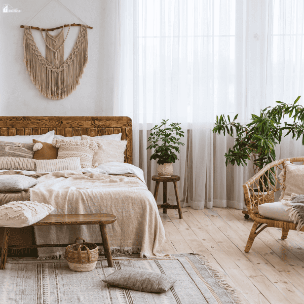 A cozy bedroom uses layered textiles, woven accents, plants, and natural decor accessories to create a fresh, inviting space.