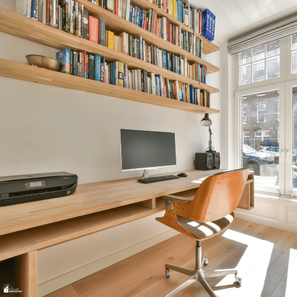 Bright home office with a built-in wooden desk and wall-mounted bookshelves that turn an unused room into a functional workspace.