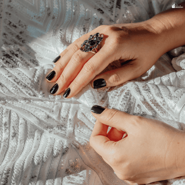 Hands gently handling delicate silver fabric to demonstrate careful garment care that helps prevent snags, stretching, and damage to expensive clothing.
