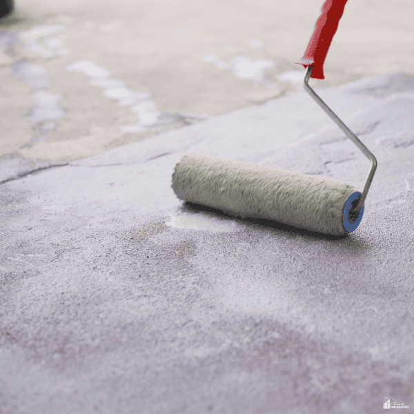 A paint roller applies a fresh coating over a concrete floor to create a smooth, updated, and stylish finish.