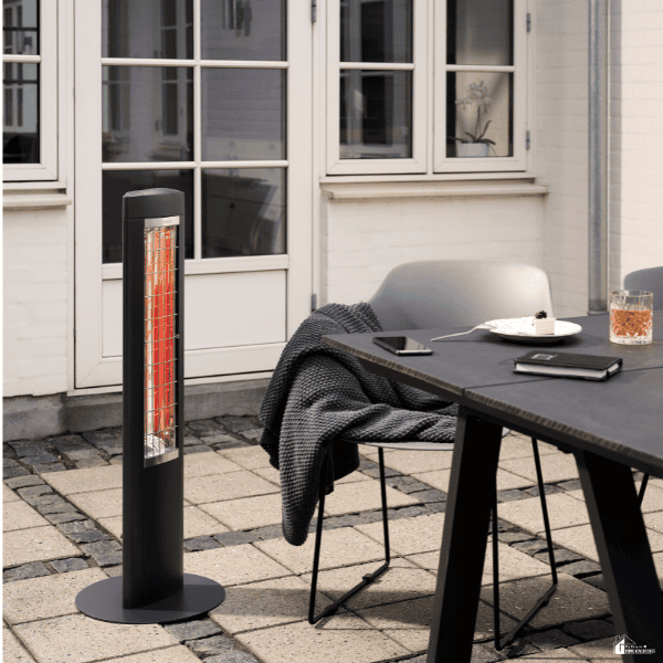 Patio dining area with a modern table, chairs, blanket, and freestanding heater for comfortable outdoor meals in cooler weather.