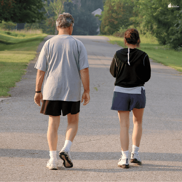 Two adults walking together outdoors on a quiet road, representing companionship, emotional support, and positive mental well-being.