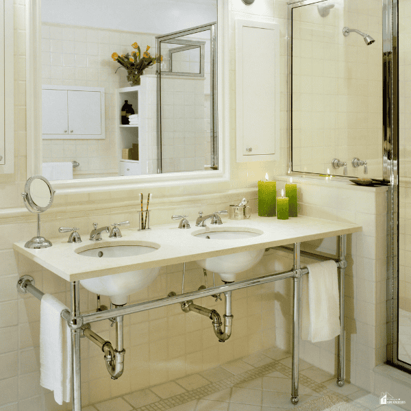 A bright renovated bathroom with a double sink vanity, large mirrors, open plumbing, and a glass shower showing an affordable home upgrade.