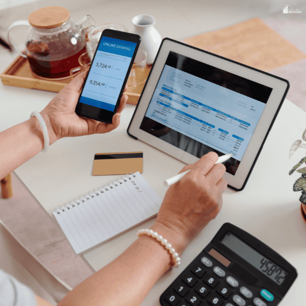 Person reviewing payroll and banking records on digital devices to assess how a minimum wage increase may affect employee pay and compensation.