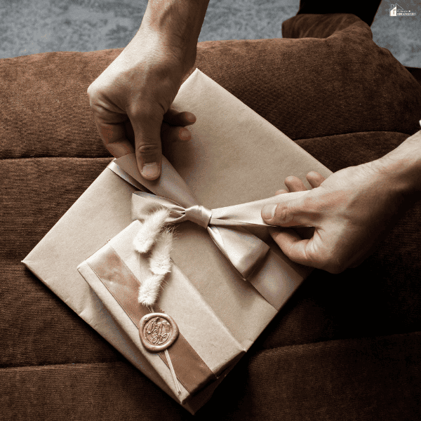 Hands wrap a present with a satin ribbon and wax seal, showing the careful packaging associated with personalized gift brands.