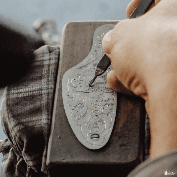 A craftsperson engraves an ornate metal keepsake, showing one way personalized gift brands customize their products.