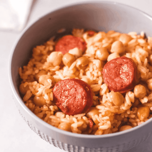 Arroz con Chorizo y Garbanzo: A gray bowl holds seasoned rice mixed with sliced chorizo and chickpeas.
