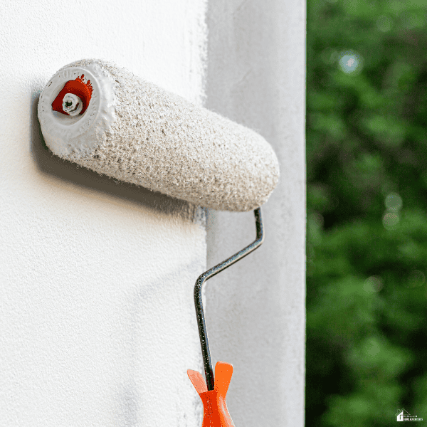A roller applies a fresh coat of paint to a wall, refreshing the home exterior and boosting curb appeal.