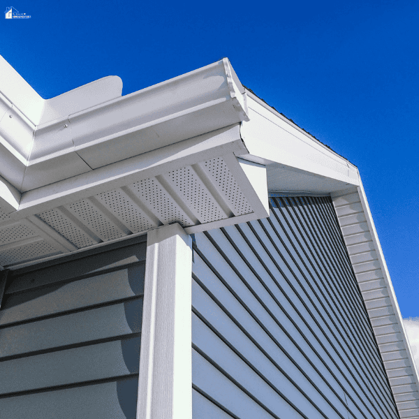 Close-up view of white ventilated soffit panels beneath a home’s roofline, showing the eaves, fascia, siding, and support post.