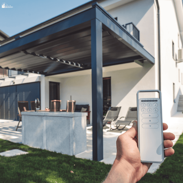 A remote controls a louvered patio cover that provides flexible shade over an outdoor seating area.