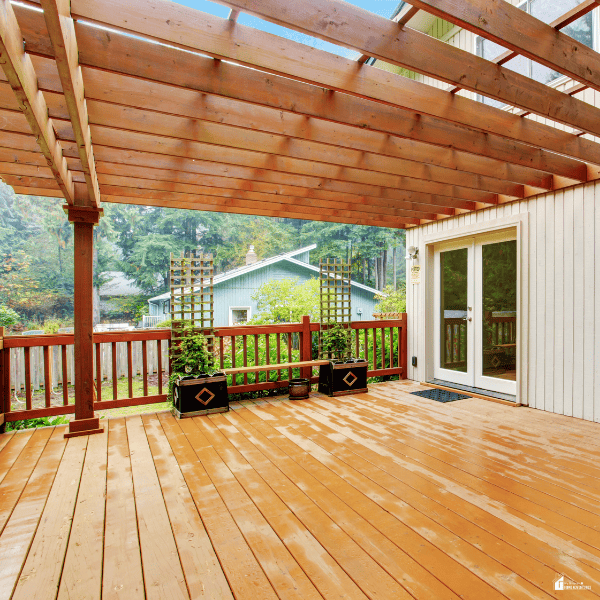 A wooden pergola provides flexible shade across a deck beside the house.