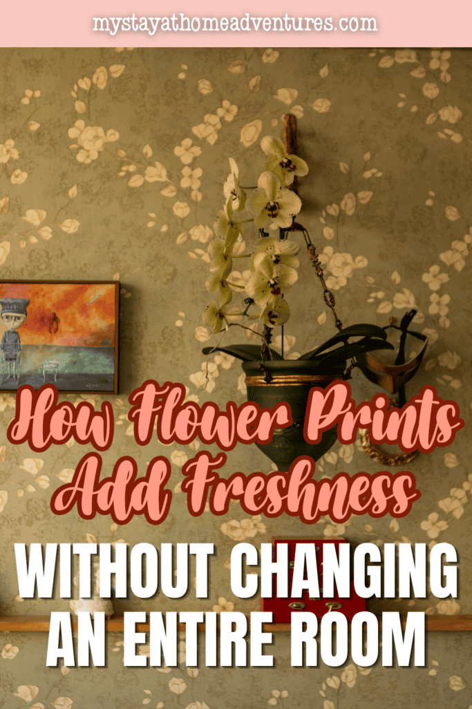 Cream flower prints spread across a muted green wall behind a potted orchid and framed artwork.