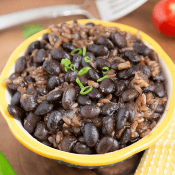 Instant Pot Black Beans and Brown Rice: Black beans and brown rice fill a yellow-rimmed bowl topped with sliced green onions.