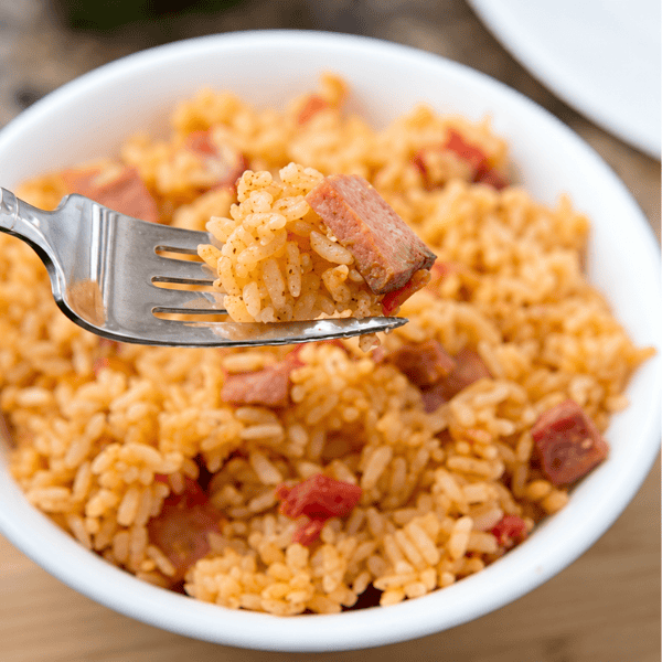 A fork scooping Instant Pot Spanish Rice from a white bowl.