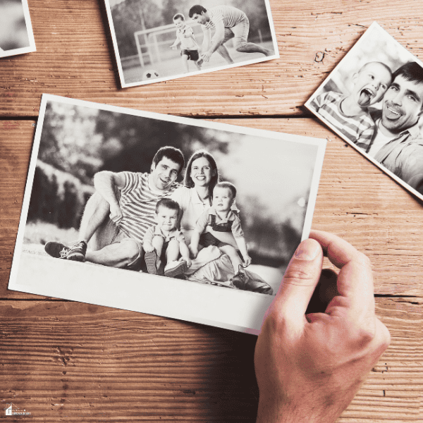 Hand holding a cherished family portrait among old photographs that preserve meaningful family memories.