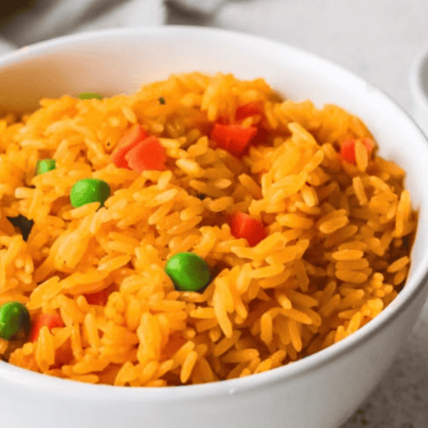 Pollo Tropical Yellow Rice: Golden yellow rice with green peas and diced red peppers fills a white bowl.