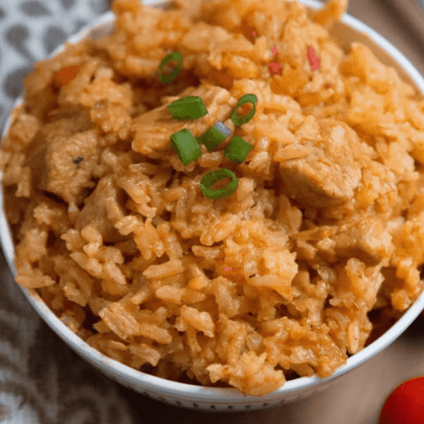Puerto Rican Rice and Pork: A white bowl holds seasoned rice with chunks of pork and sliced green onions.