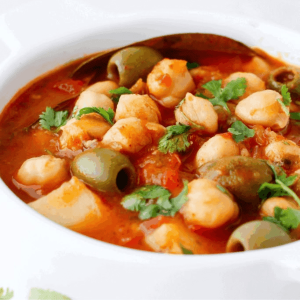 Puerto Rican Stewed Chickpeas: Chickpeas, potato chunks, and green olives sit in a red sauce topped with fresh cilantro.