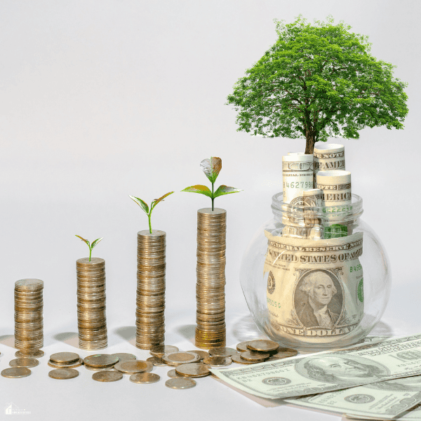 Increasing stacks of coins with green plants lead toward a money-filled jar and tree, symbolizing savings growth and long-term wealth.