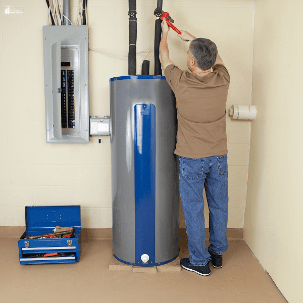 A technician adjusts pipes above a household heater that supplies hot water for daily use.