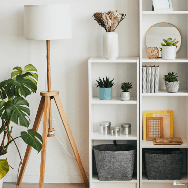 Stylish shelving with plants, storage baskets, framed decor, and a floor lamp showcasing products for a home decor business.