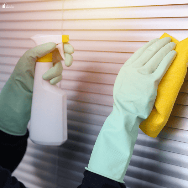Gloved hands clean horizontal blinds that can be adjusted to reduce heat and glare.
