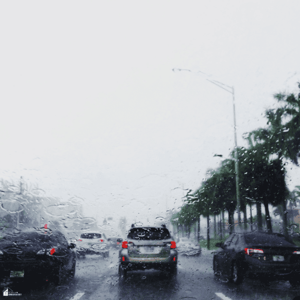 Rainy residential commute with cars and palm trees, representing location factors to consider when planning more living space for a Jacksonville home.