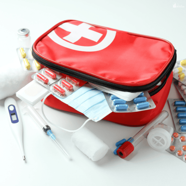 Family travel health kit filled with medications, a thermometer, bandages, gauze, a face mask, and other useful medical essentials for trips.