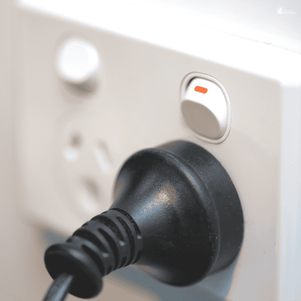 A black plug fills a wall outlet, showing one household connection to consider during an electrical upgrade.