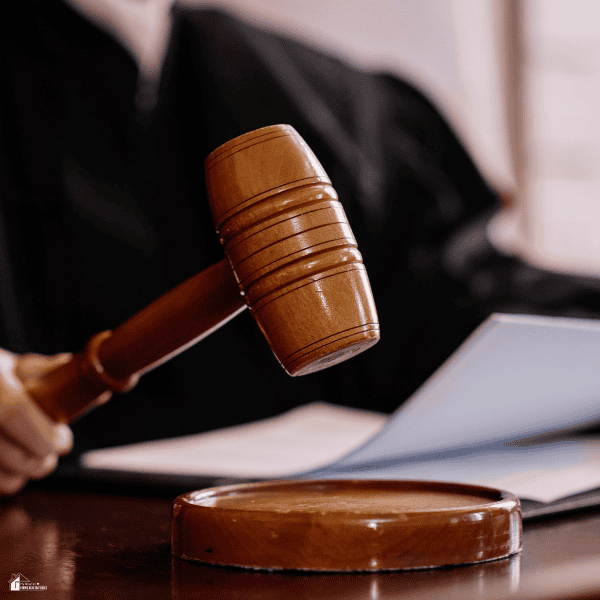 A wooden gavel rests above its base beside documents representing the court process for injury claims.