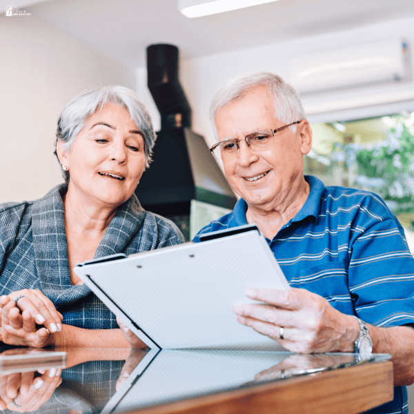An older couple reviews paperwork together, illustrating planning for a move to a retirement village.