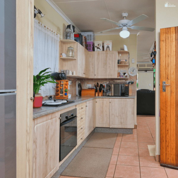 A compact kitchen with pale wood cabinets and terracotta flooring shows layout considerations to discuss with renovation companies.