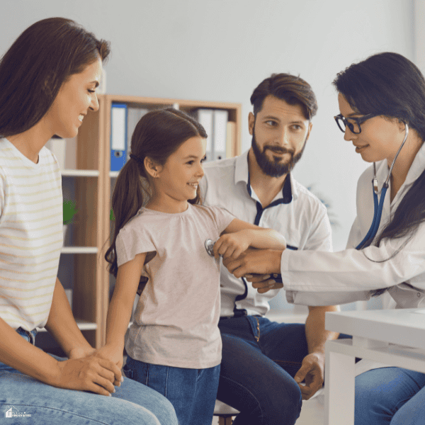 A doctor examines a young girl beside her parents, illustrating family medical care relevant to comprehensive overseas visitors insurance.